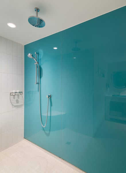 Shower with glass door and turquoise back painted glass