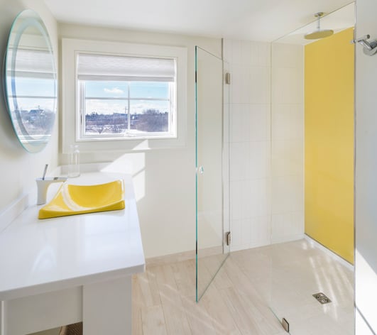 Bathroom with yellow back painted glass and clear glass shower door