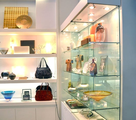 Retail glass shelves with boutique products and handbags sitting on top