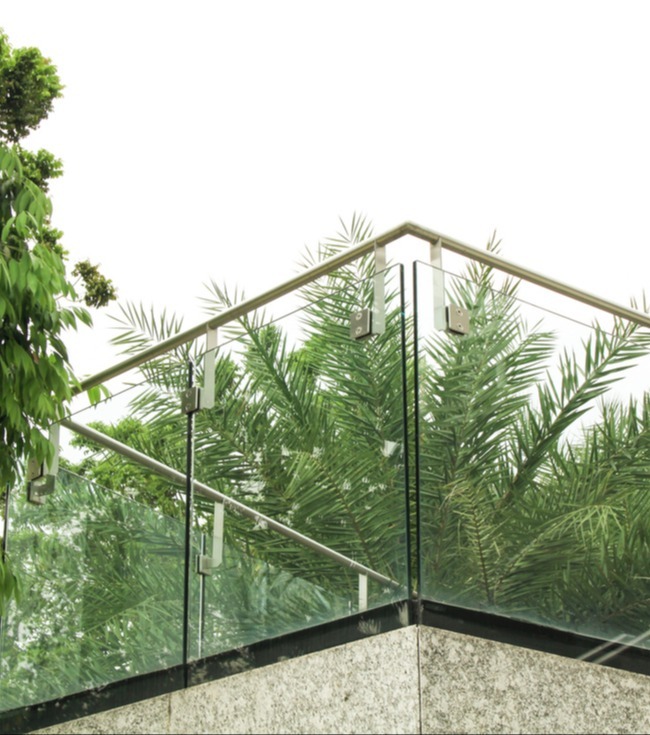Glass outdoor railing with greenery in the background