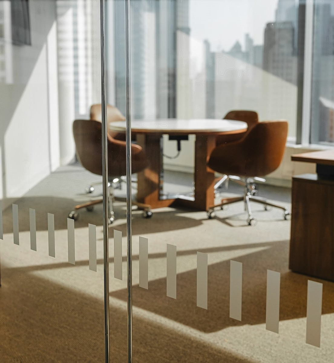 Glass office doors with custom decoration, looking in on modern office desk and chairs