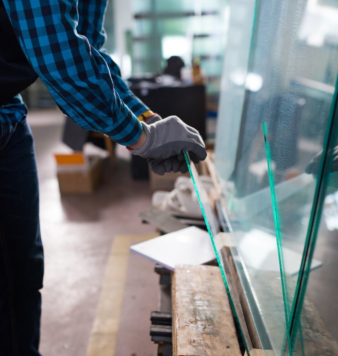 Worker handling glass pieces in warehouse