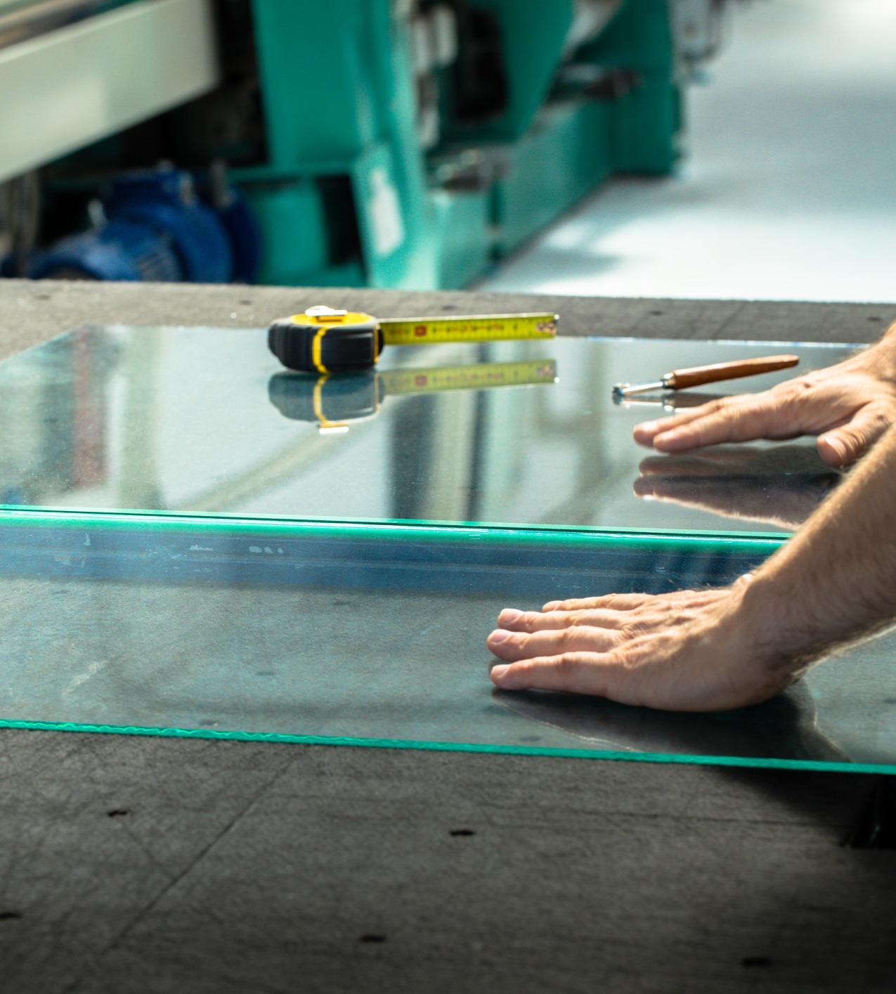Worker measuring with tape measure to cut glass