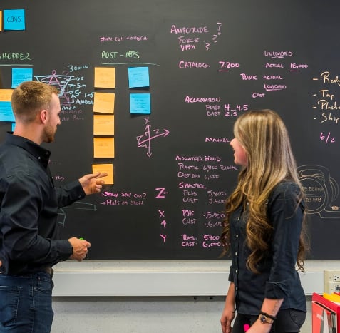 man and woman looking at markerboard