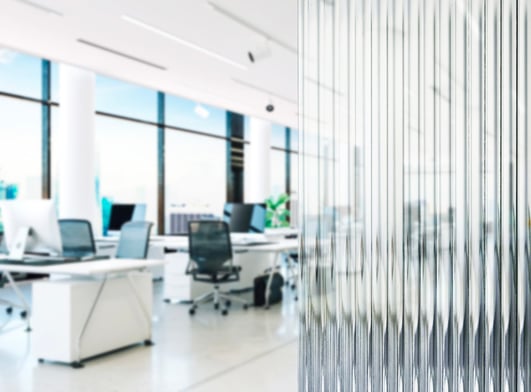 well lit office in the background with a rippled glass wall on the right side of the image